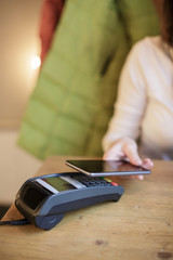 Woman pays the bill in the cafe with their smartphone with wireless payment