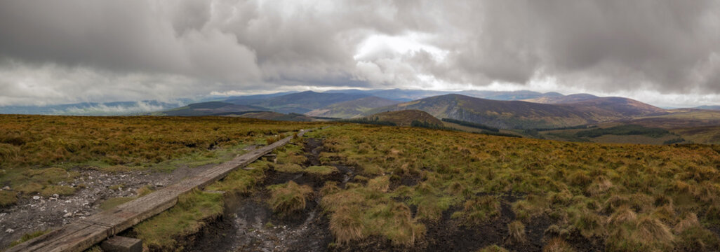 Wicklow way trail leading to the vibrant irish panorama landscape with moody overcast clouds