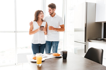Fototapeta premium Couple standing and hugging in front of table with breakfast