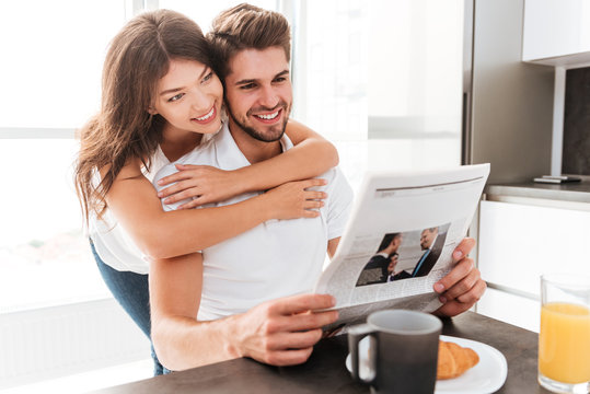 Couple hugging and reading newspaper on the kitchen