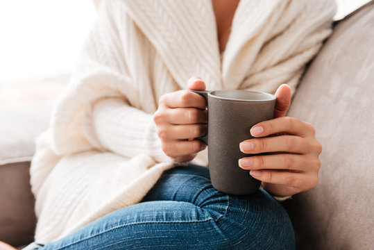 Woman sitting and holding cup of coffee on couch