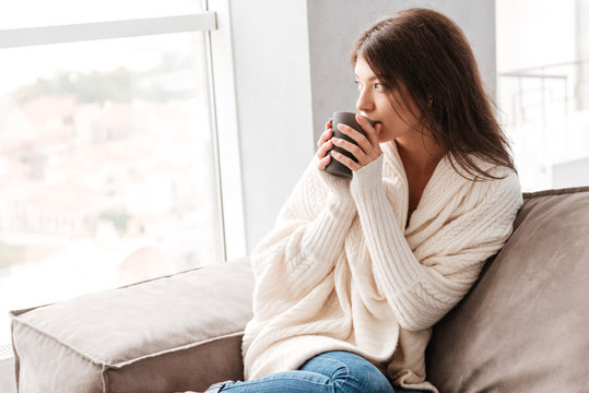 Pensive woman thinking and drinking coffee at home