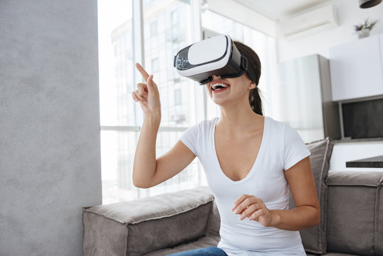 Smiling young woman using virtual reality googles at home