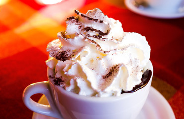 cup of coffee latte with whipped cream and chocolate in a dark light vintage style