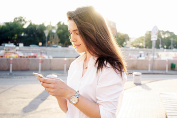 A travel blogger is using route application on the mobile phone to find the needed address in a city. A brunette woman is reading emails on the smartphone.