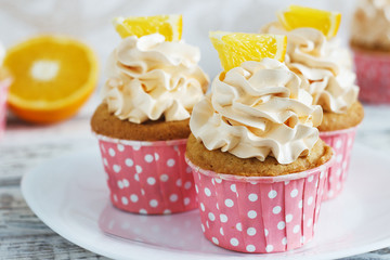 Vanilla cupcakes with a cap of cream on white wooden tablein