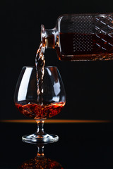 Naklejka na ściany i meble Glass of brandy on a black background