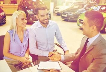 happy couple with car dealer in auto show or salon