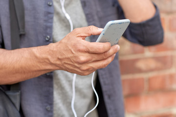 close up of man with smartphone and earphones wire