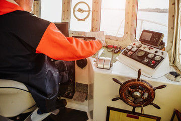 Man fishing vessel captain in the ship's wheelhouse. The control system, navigation system. Fishing, industry, fishery. © scharfsinn86