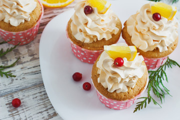 Christmas cupcakes with whipped cream topping and cranberries,orange. festive food dessert.