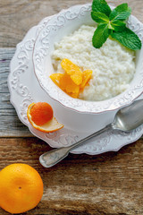 Bowl with rice porridge, slices of mandarin and mint.