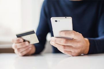 Male hands holding credit card and using smart phone. Online shopping concept
