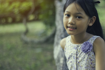 Little asian girl smiling in the park, close up.