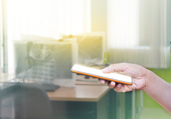 Hand holding mobile smartphone on office background.