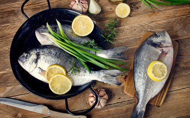 Fresh fish with herbs and spices on wooden background.