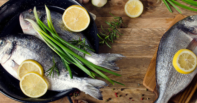 Fresh fish with herbs and spices on a wooden background.