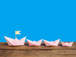 Leadership concept, Pink paper boat group (Origami) on wooden ta