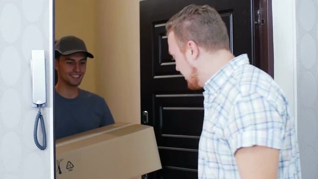 The young and friendly courier brought a parcel to the man