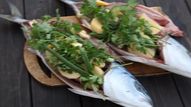 Fresh Fish on wooden background. Yellowtail Amberjack. Stuffed with apples, lemon and fresh herbs