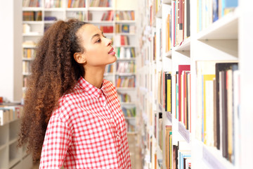 Biblioteka uniwersytecka. Kobieta szuka książki na regale w bibliotece. © Robert Przybysz