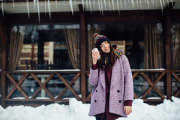 Portrait happy and beautiful girl in winter street heated coffee and smile.