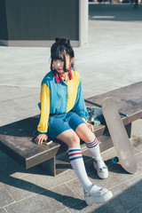 young beautiful asian millennial woman listening music with earphones and smart phone hand hold...