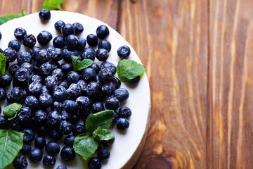 Sweet creamy blueberry cheesecake with fresh blueberries and mint leaves on a wooden background with copy space. top view.