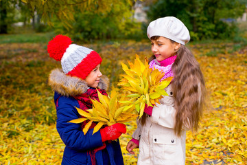 two little girls in autumn park with leafs