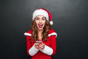 Excited woman in red santa claus outfit with mobile phone