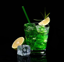 Green tarragon drink with ice cubes, lime on a black  background