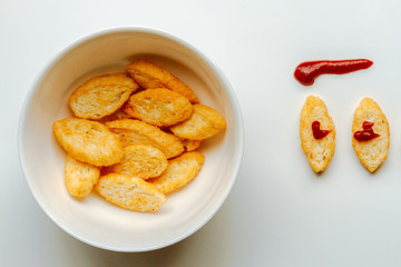 Toasts next to white bowl full of toast with olive oil and ketch