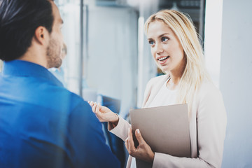 Fototapeta premium Two coworkers discussing business project in modern office.Successful confident hispanic businessman talking with woman. Horizontal, blurred background.