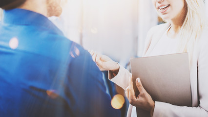 Two coworkers discussing business project in modern office.Successful confident hispanic businessman talking with blonde woman. Horizontal closeup, flare, blurred background.