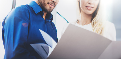 Concept of teamwork.Businesswoman showing a finance report to the colleague.Two coworkers making great business project discussion in modern office.Horizontal closeup, blurred background.