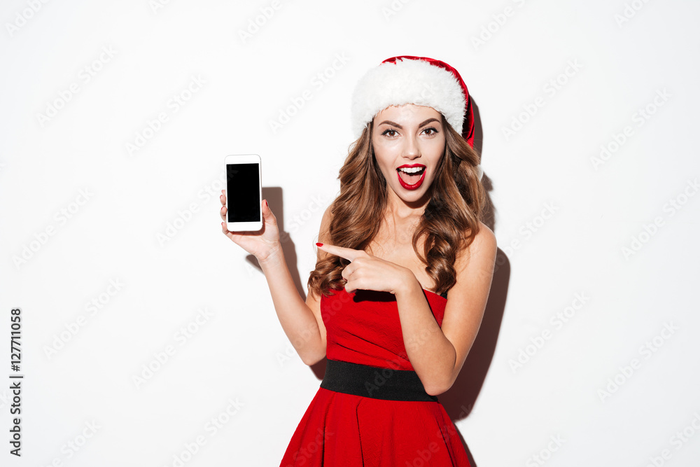 Sticker woman in santa claus hat pointing at blank screen smartphone