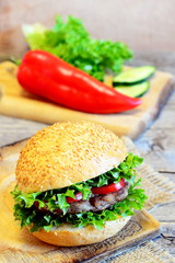 Sandwich with a bean cutlet, lettuce, red pepper and cucumber. Hearty sandwich on a wooden board, fresh vegetables. Simple vegetarian breakfast sandwich idea. Vintage style. Closeup