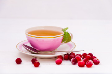 Pink cup of tea and cranberries on white background