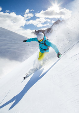 Skier skiing downhill in high mountains