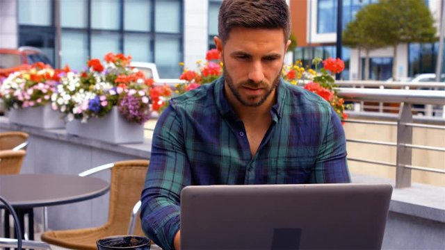 Businessman having a cup od coffee while using laptop