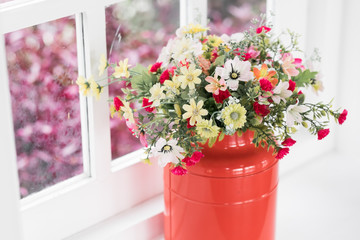 Colorful decoration artificial flower against window background.