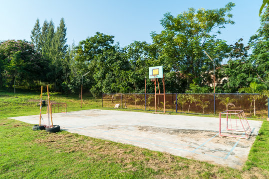 Basketball hoop in the park with green trees in background