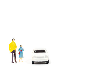 Miniature figures of people and car on white background