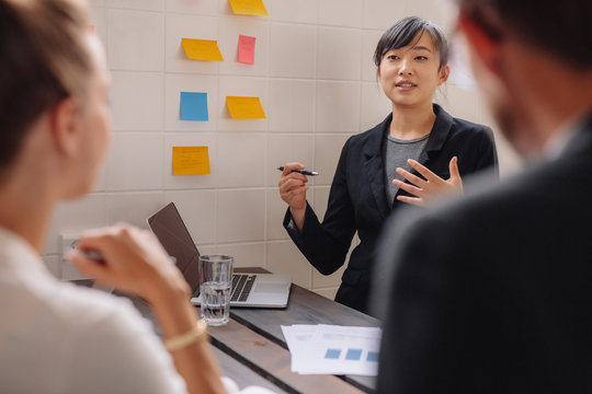 Young female executive giving presentation to colleagues