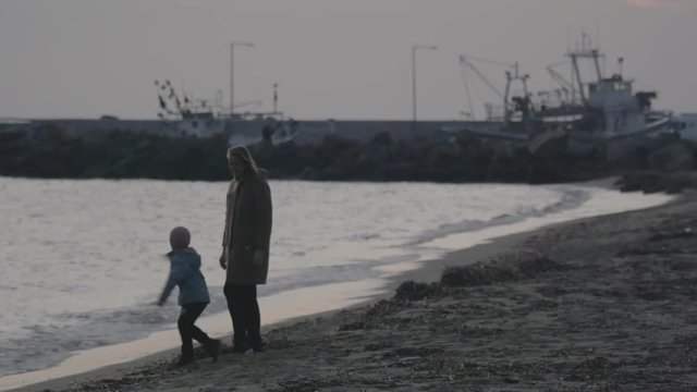 Mother with son walking and playing on the beach of Aegean Sea in the winter Nea Kallikratia, Greece