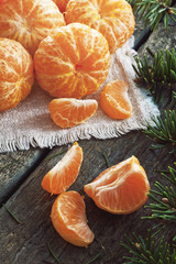 Peeled tangerines on a wooden background and fir branch