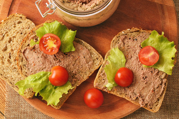 Chicken liver pate on the bread on wooden tray.