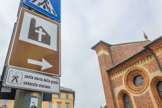 close up on road sign to Milan's Saint Mary church , Santa Maria Delle Grazie, hosting The Last Supper mural painting by Leonardo da Vinci. left side street view.