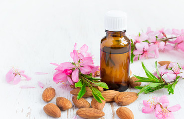 Essential almond oil, flowers and nuts on a white background