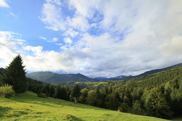 Gree mountain landscape with cloudy blue sky and coniferous forest